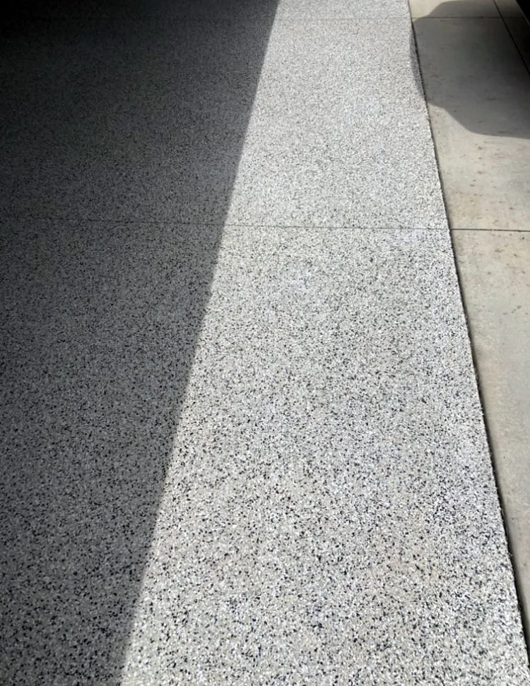 Flake epoxy coating meeting bare concrete at a garage threshold