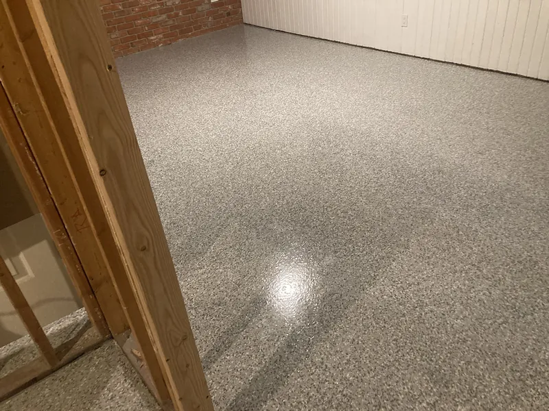 Flake epoxy garage floor beside brick and wood framing